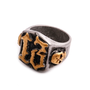 Makroaufnahme von Vintage-Stahlring mit Gravur Nummer 13 und goldenem Totenkopf-Relief