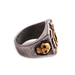 Detailansicht eines gotischen Totenkopf-Rings mit geprägtem Goldkreuz und Schwertdesign