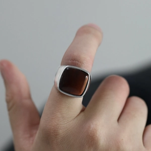 Détail macro d'une bague vintage pour homme en acier avec pierre précieuse carrée rouge