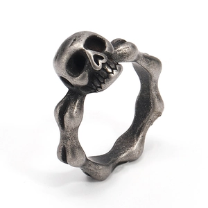 Primer plano del anillo de calavera motera vintage con banda en forma de hueso plateado
