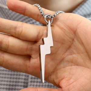 Detail view of lightning bolt steel pendant held in hand for size visualization
