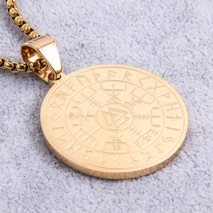 Detailed macro view of a gold Viking compass pendant with runes on stainless steel chain