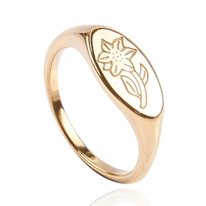 Gros plan d'une bague chevalière dorée ornée d'un motif floral délicatement gravé