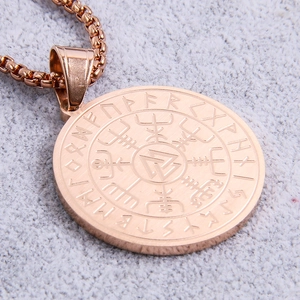 Macro shot of rose gold Viking Vegvisir and Valknut symbols engraved on steel pendant
