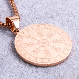 Macro shot of rose gold Viking compass pendant with Nordic runes and polished steel chain