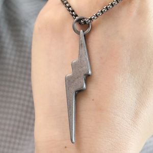 Macro detail of lightning bolt pendant in vintage silver titanium steel on neck