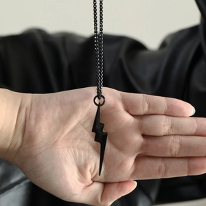 Close-up of black lightning bolt pendant on a stainless steel square box chain necklace