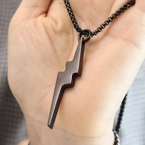 Close-up of black lightning bolt pendant on a square link chain held in hand