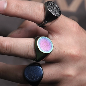 Detail of vintage compass rings with mystical symbols in silver, blue, and rainbow finishes