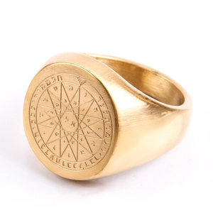 Macro shot of gold compass ring with engraved heptagram and mystical occult symbols