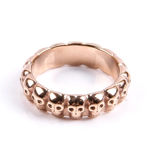Dettaglio macro dell'anello punk in acciaio al titanio oro rosa con teschi a rilievo