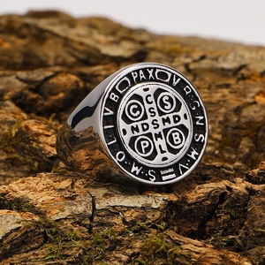 Macro shot of silver Saint Benedict Medal signet ring on natural mossy bark background