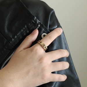 Detailed close-up of a gold-plated Cuban link chain ring worn on a person's index finger