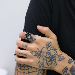 Detail of adjustable stainless steel double skull ring on tattooed hand punk style
