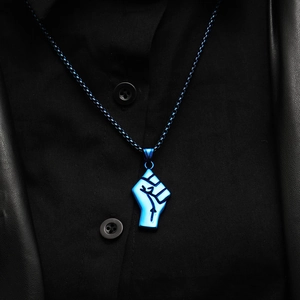 Dettaglio della collana con pendente a pugno blu elettrico su abbigliamento nero