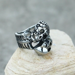 Gothic punk dual skull ring in polished stainless steel on natural stone surface