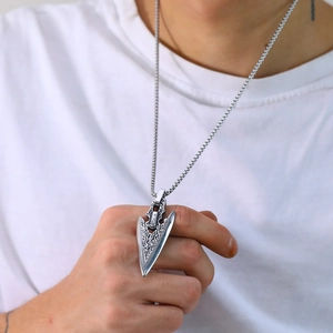 Detail of vintage silver arrow pendant with tribal patterns and box chain for men