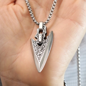 Close-up of vintage stainless steel arrowhead pendant with textured embossed details
