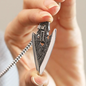 Macro detail of sword arrowhead pendant showing intricate hollow texture and steel finish