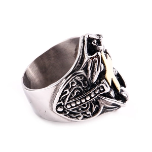 Close-up of vintage stainless steel cross skull ring with embossed sword and scrollwork