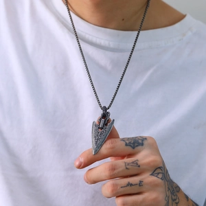 Close-up of vintage stainless steel arrow pendant with textured finish on ball chain