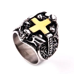 Close-up of gothic stainless steel ring with golden cross, skulls, and bat wings