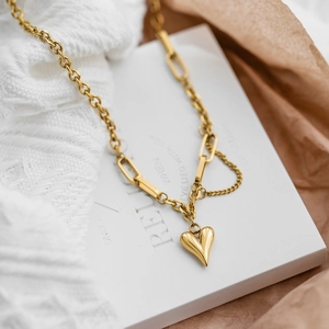 Goldene Herzanhänger-Halskette mit gemischter Gliederkette auf minimalistischem Hintergrund