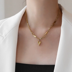Detail einer eleganten goldenen Herzkette mit asymmetrischer Gliederkette am Model