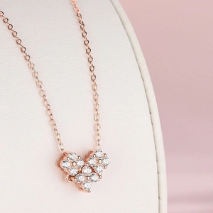 Vista macro de colgante de corazón en oro rosa con pavé completo de circonitas blancas