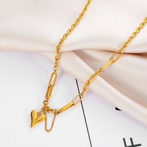 Detailaufnahme einer goldenen Herz-Halskette mit Gliederkette auf seidigem Stoffhintergrund