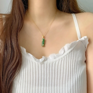 Élégant collier en acier titane doré avec pendentif bambou vert sur un mannequin