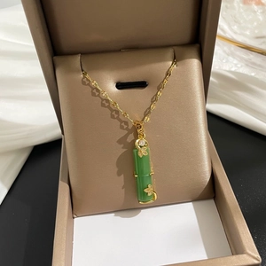 Détail d'un collier en bambou doré avec pendentif en jade vert dans un coffret bijoux