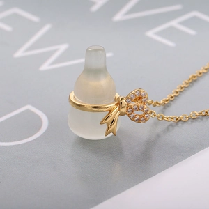 Elegante collana in titanio dorato con ciondolo a biberon traslucido e fiocco d'oro
