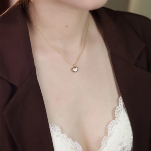 Detail of a vintage heart necklace with white mother of pearl inlay on gold chain