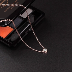 Close-up of a 18K rose gold necklace featuring a single round diamond bubble pendant