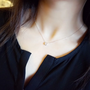 Macro shot of a minimalist 18K rose gold necklace with a round solitaire bubble pendant
