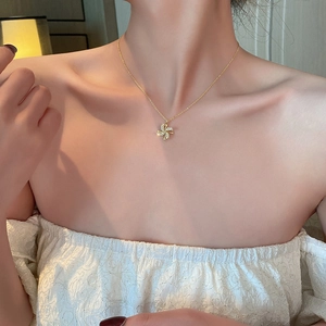 Close-up of a rotating gold windmill necklace with sparkling zircon crystals on a model