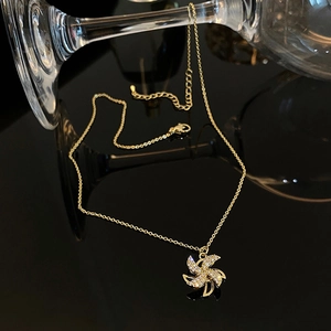 Macro shot of rotating gold windmill pendant with white zircons on a black background
