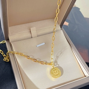 Goldene Büroklammer-Halskette mit Tiger-Anhänger auf einer braunen Schmuckschatulle