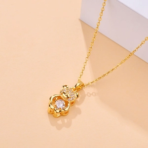 Golden bear pendant necklace with sparkling cubic zirconia on a warm beige background