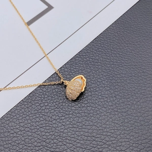 Elegante collana con ciondolo a conchiglia dorata con cristalli e perla bianca lucida
