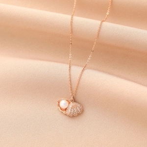 Vista dettagliata di un ciondolo a conchiglia in oro rosa con micro-zirconi e perla bianca