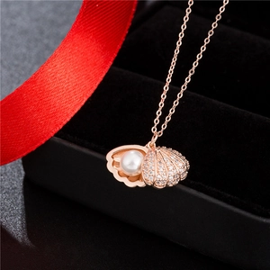 Vista macro della collana con ciondolo a conchiglia oro rosa con cristalli e perla bianca