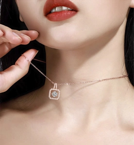 Detail of rose gold pendant necklace with square frame and dancing cubic zirconia on skin