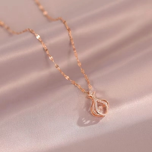 Macro detail of rose gold handbag pendant necklace with pavé crystals on pink silk