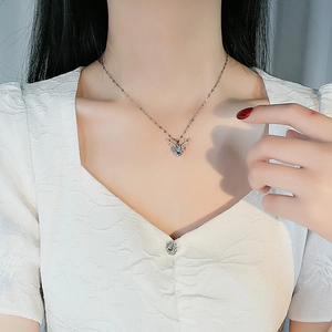Elegant silver reindeer pendant necklace with crystals worn by a model on a white top