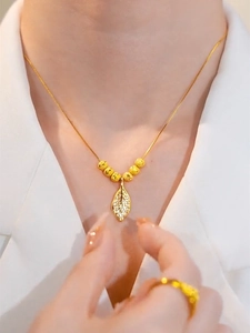 Close-up of gold leaf pendant necklace with crystals and matching ring on model