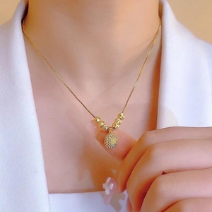 Golden necklace with sunflower pendant and textured beads worn on a model with a white suit