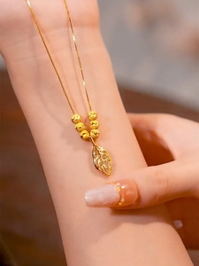 Detail view of a gold leaf pendant necklace with frosted beads and diamonds on neck