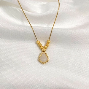 Detailed view of a gold Buddha pendant with white jade and sparkling zircon inlay work